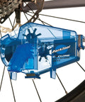 Cyclone Chain Scrubber CM-5.3 in blue attached to bike chain, showing easy grip handle and mess-free solvent wicking sponge.