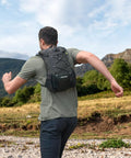Man running with Ultra Lightweight Hydration Backpack for Runners and Cyclists, 2L Water Bladder in a scenic outdoor setting.