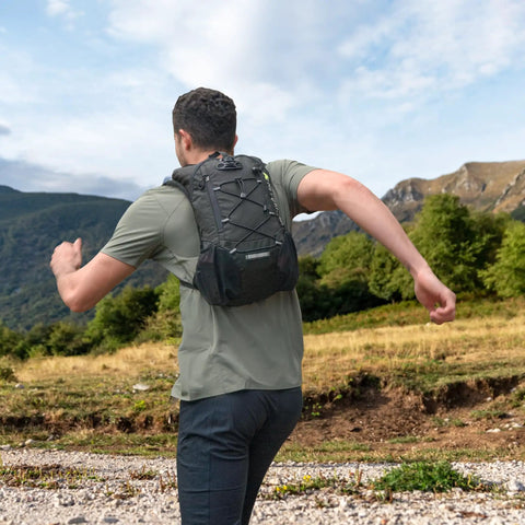 Man running with Ultra Lightweight Hydration Backpack for Runners and Cyclists, 2L Water Bladder in a scenic outdoor setting.