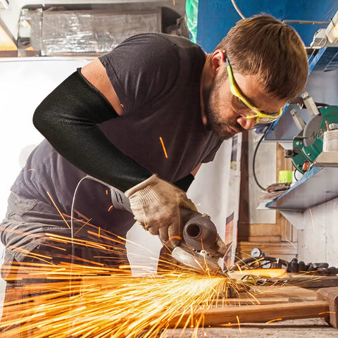 Man using a grinder wearing black Level 5 Cut Resistant Arm Sleeves With Thumb Hole 18 Inch Long For Gardening And Farm Work.