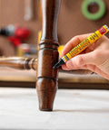Person using No Sweat Wood Finish Stain Marker Pen for quick touch ups on furniture leg in dark ebony shade.