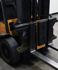 FCB-818 Class II Fork Truck Carriage Bumper With Molded Rubber And Steel mounted on forklift tines, black and yellow finish.
