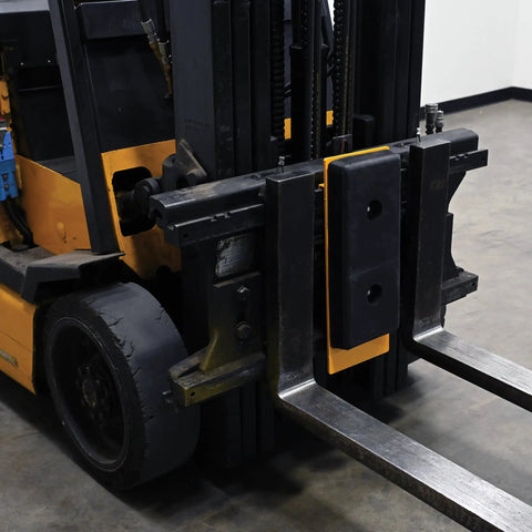 FCB-818 Class II Fork Truck Carriage Bumper With Molded Rubber And Steel mounted on forklift tines, black and yellow finish.