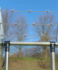 10 Pack Barbed Wire Arm For One And Three Eighths Inch Chain Link Fence Height Extender Galvanized Steel For Garden And Outdoor Fences Increase Height, Boost Privacy, And Keep Pets From Jumping DIY Friendly Install on a chain-link fence with trees in the background