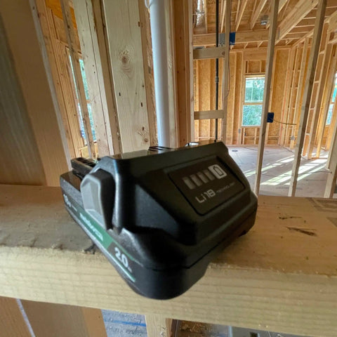 18V 2.0Ah Lithium Ion Battery with Fuel Gauge on wooden beam in construction site, showcasing lightweight slide type pack