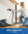 Quiet Bagless Canister Vacuum With Kickass Suction For Whole Home Cleaning. User cleaning stairs with vacuum and hose.