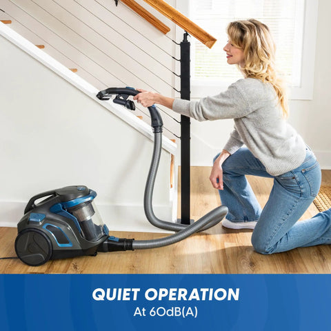 Quiet Bagless Canister Vacuum With Kickass Suction For Whole Home Cleaning. User cleaning stairs with vacuum and hose.