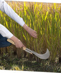 Person using Manganese Steel Long Handle Weeding Sickle for Grass Vines and Branches in garden