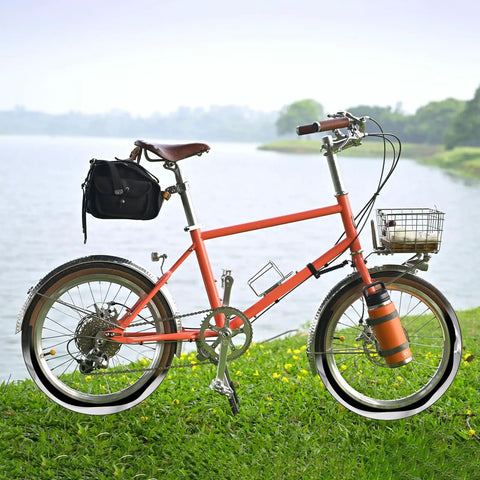 Orange bicycle with basket and bag beside lake, highlighting use of Self Sealing Bike Inner Tubes 20x1.75 to 2.125 AV32mm With Schrader Valve