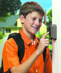 Young boy using Push Button Key Safe With Permanent Combination Lock Box For 2 Keys on wall, Titanium Gray with Black Weather Shield.
