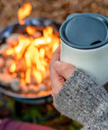 Cozy scene with person holding mug near Portable Propane Fire Pit 19 Inch Smokeless Gas Firebowl With Carry Kit And Cover, 58,000 BTU.