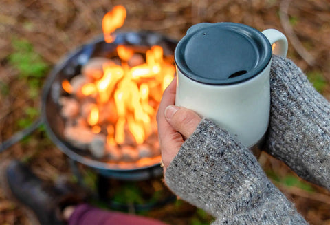 Cozy scene with person holding mug near Portable Propane Fire Pit 19 Inch Smokeless Gas Firebowl With Carry Kit And Cover, 58,000 BTU.