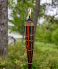 Close-up of 60 Inch Bamboo Torches 4-Pack With Easy Pour 12 Oz Canisters, Long-Lasting Fiberglass Wicks And Snuffers in walnut finish outdoors.