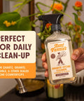 Person holding Granite And Stone Daily Countertop Cleaner With Plant Based Formula, ideal for quartz and stone surfaces, in kitchen.