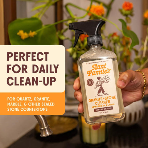 Person holding Granite And Stone Daily Countertop Cleaner With Plant Based Formula, ideal for quartz and stone surfaces, in kitchen.