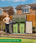 Outdoor Trash Can Storage Shed With 46 Cu Ft Capacity, Waterproof Horizontal Cabinet, Dark Grey Outdoor Storage Solution For Bikes And Yard Gear, Weatherproof, Easy Install And Durable Shed For Patio with double doors open showing green bins.