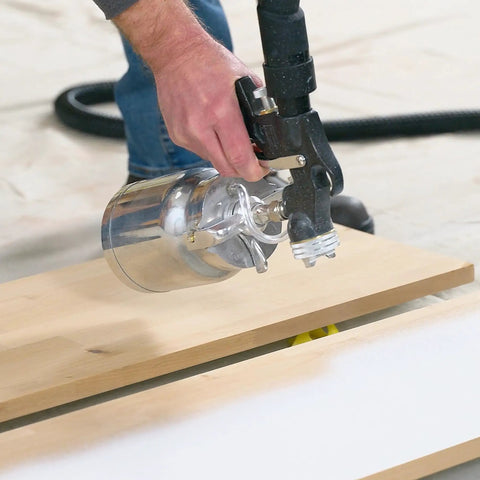 Hand using a stationary HVLP finishing sprayer for woodworkers wanting killer results on furniture restoration projects.