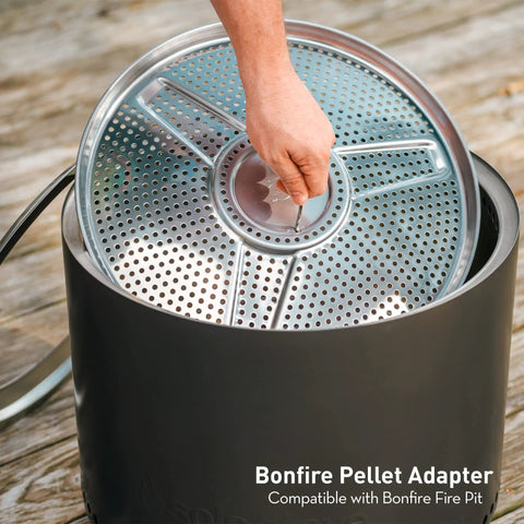 Person placing Bonfire Pellet Adapter for Outdoor Fire Pits Dual Fuel Upgrade into a fire pit, showing stainless steel extension.