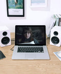 SW208 3 Inch Active Bluetooth 5.0 Bookshelf Speakers Pair With 60 Watt Output Carbon Fiber Drivers Built In 24 Bit DAC Dynamic 3D Surround Sound Crisp Highs And Punchy Bass For Gaming And Monitor Setup White Finish next to laptop on desk