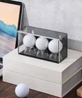 Baseball And Golf Ball Display Case For Three Balls With UV Protected Acrylic Box Memorabilia Showcase For Autographs And Cube Displays Black Finish 5.9 By 2.4 By 1.8 Inches on desk with golf balls nearby