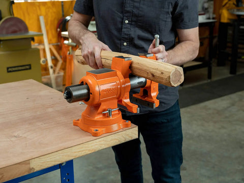 Heavy Duty 5 Inch Multi Purpose Swivel Base Bench Vise With 3 Jaw Styles Rotates 360 Degrees, holding wood, in workshop