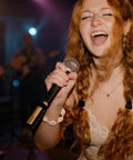 Singer using Spark Link XLR Wireless System For Dynamic Microphones Pro Grade Studio Audio on stage, close-up view.