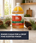 Top Shelf Pine Burst Multi Surface Cleaner in a 1-gallon container with pine sprigs and pinecones on a kitchen counter.
