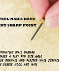 Close-up of a hand holding a nail from 100 Pieces Picture Hanging Nails Set 0.16 x 0.98 Inch Wall Hanger Nails For Drywall Holds 5-30 Lbs