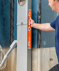 Person using Magnetic Heavy Duty I Beam Aluminum Level 24 Inch In Orange With Oversized Vials And Hands Free Setup on wall
