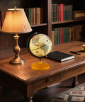 Six Inch Mini Vintage Rotating Globe With Curved Alloy Stem And Solid Wooden Base on a wooden desk in a cozy home office setting.