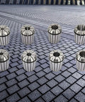 8 Piece ER Balance Collet Set in manganese steel on tiled surface for CNC milling and lathe engraving, showcasing durability and precision.