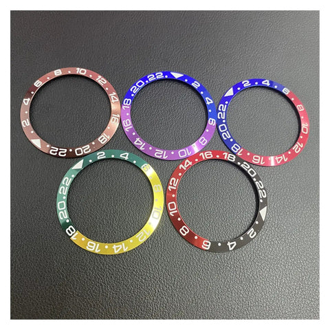 Various colored ceramic bezel inserts for 43mm Sea-Dweller GMT watch, including brown, for DIY repairs and upgrades on black surface.