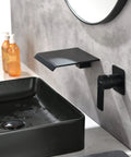Wall Mount Bathtub Filler Faucet With Waterfall Flow, matte black finish, solid brass, beside a modern matte black sink