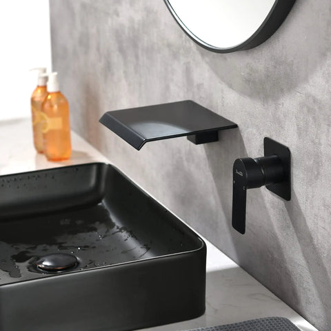 Wall Mount Bathtub Filler Faucet With Waterfall Flow, matte black finish, solid brass, beside a modern matte black sink