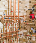 Complex plumbing system with pipes, valves, and pressure gauges in a utility room.