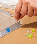 Pro Stained Glass Layout Block System With Sixty Mixed Color Push Pins Tracing Board with a hand placing a green pin.