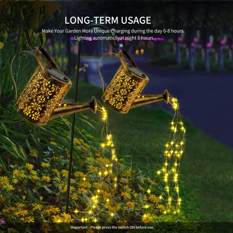 Copper Solar Watering Can Garden Light With Waterfall Effect And 60 LEDs illuminating a flower bed at night.