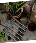 High-Performance Steel Soil Loosening Fork With Four-Tooth Design shown with plants and soil, ideal for heavy-duty garden prep.