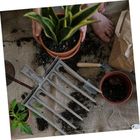 High-Performance Steel Soil Loosening Fork With Four-Tooth Design shown with plants and soil, ideal for heavy-duty garden prep.