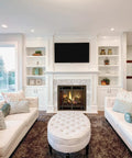 Elegant living room with white sofas, large windows, and a fireplace with built-in shelves displaying decor.