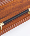 Brushed Satin Gold Bar Cabinet Handle With Black Leather Upholstery 8.5 Inch Overall Length, mounted on wooden surface
