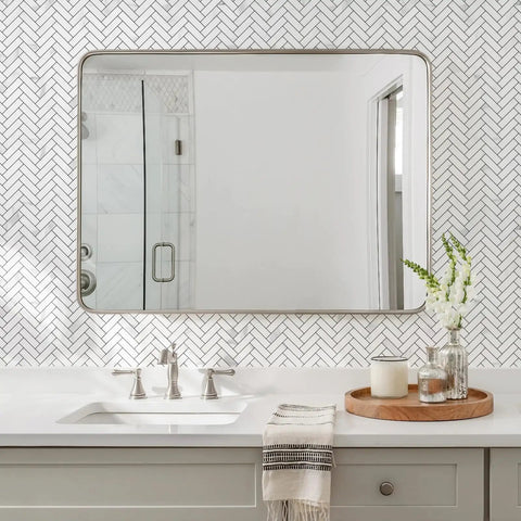 Bathroom scene with Peel And Stick Herringbone Kitchen Backsplash Tiles Self Adhesive Aluminum Composite PVC Marble White With Light Grey Veining For Easy DIY Install And Modern Look 7.7 Sq Ft Coverage Includes Bonus Gloves behind mirror.