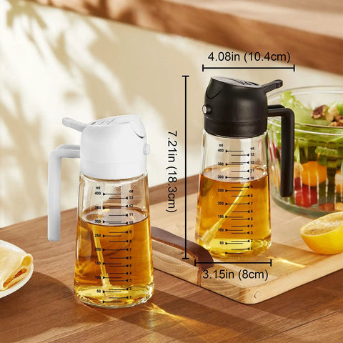 Game Changing Glass Olive Oil Sprayer For Cooking, 16 Oz Dual Pump Dispenser Bottle next to a salad and lemon on a wooden table.