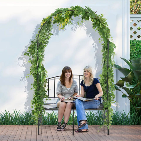 Two women seated on 81 Inch Garden Arch With Bench Outdoor Arbor Trellis For Climbing Plants And Vines Two Seat Bench Supports Up To 660 Lbs Ideal Patio Pergola For Weddings Parties And Scenic Garden Entry Decor.