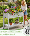 Raised Garden Bed On Wheels With Storage Shelf And Water Level Monitor in backyard with colorful flowers and woman pushing
