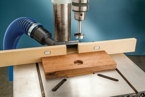 Dust Right Port for Drill Press Fence Portable Dust Collection Attachment with upward angled hose and wood piece on a drill press