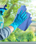 Cleaning a window with blue Huck towels, spray bottle in hand. Blue Huck Towels 50 Pack Bulk Absorbent Cotton Shop Towels