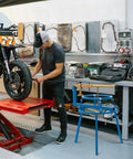 Mechanic using Heavy Duty Pro Grade Motorcycle Tire Changer Stand For 16 To 24 Inch Tires in workshop with motorcycle on lift.