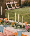 Flameless Taper Candle Set 4 Pack 9 Inch Ivory Wax With Realistic 3D Wick Flame arranged on outdoor dining table with decor.
