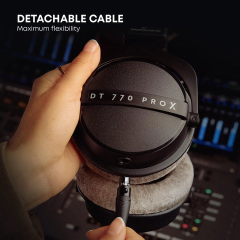 Hands holding DT 770 Pro X Wired Studio Headphones 48 Ohm Closed Back For Recording And Mixing, showing detachable cable feature.